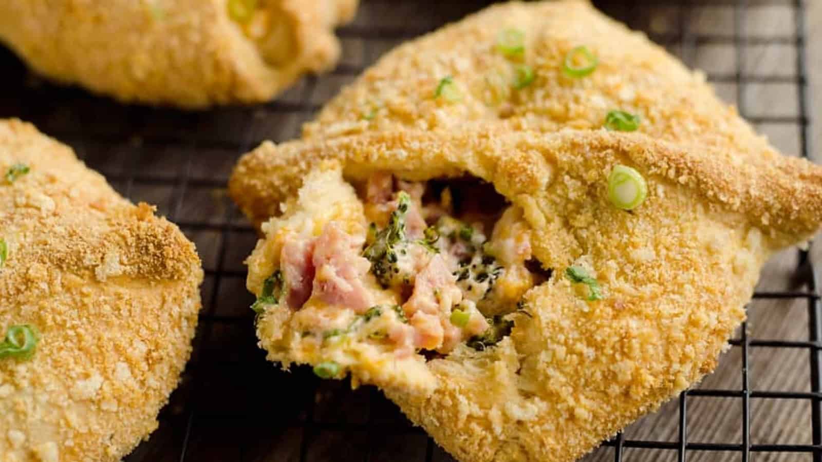 Golden baked pastry filled with ham, broccoli, and cheese on a cooling rack, garnished with green onions.