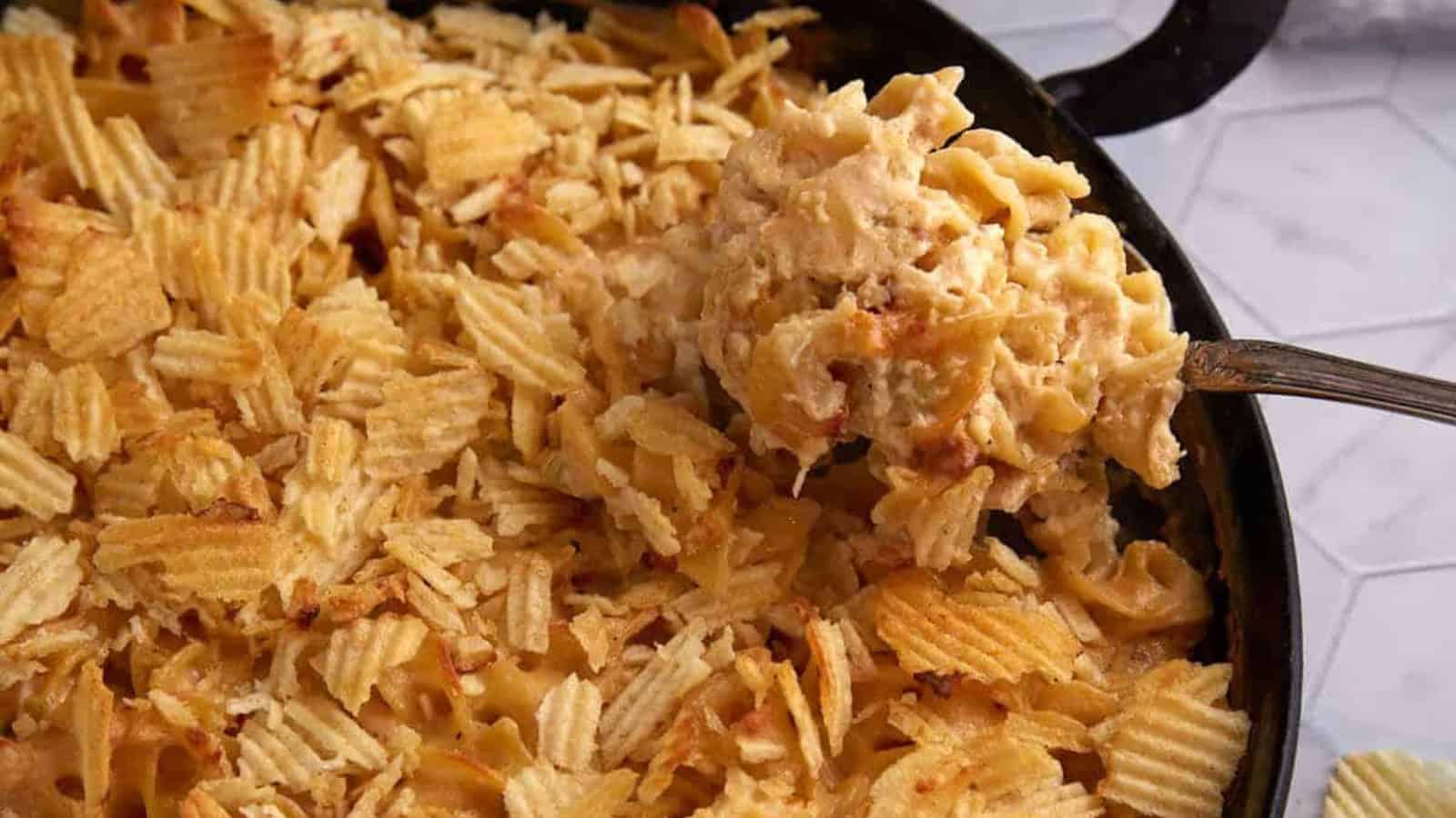 A casserole topped with crispy potato chips, with a serving being lifted out on a large spoon.