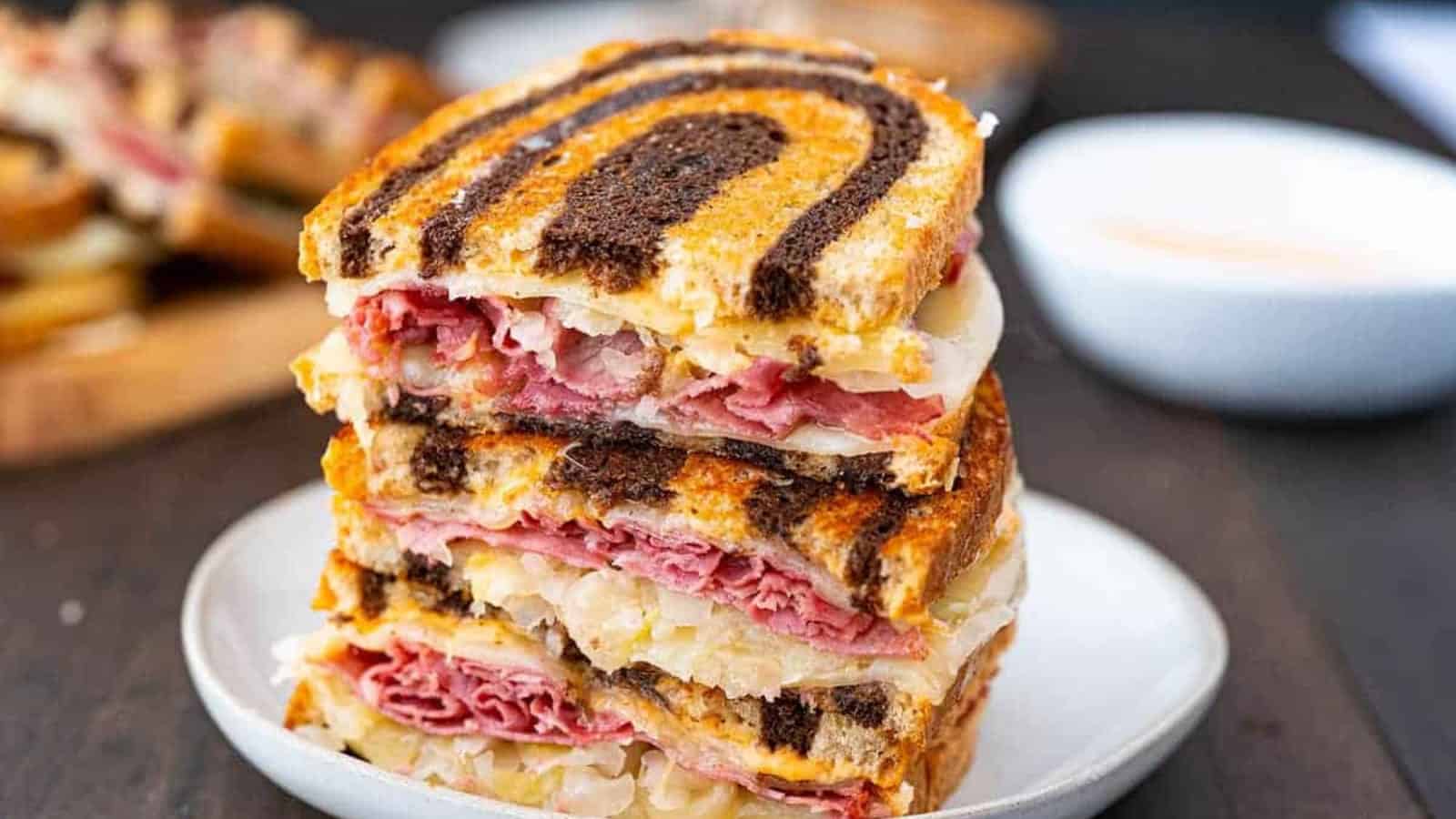 Three stacked Reuben sandwiches on marbled rye bread, filled with corned beef, sauerkraut, and cheese.