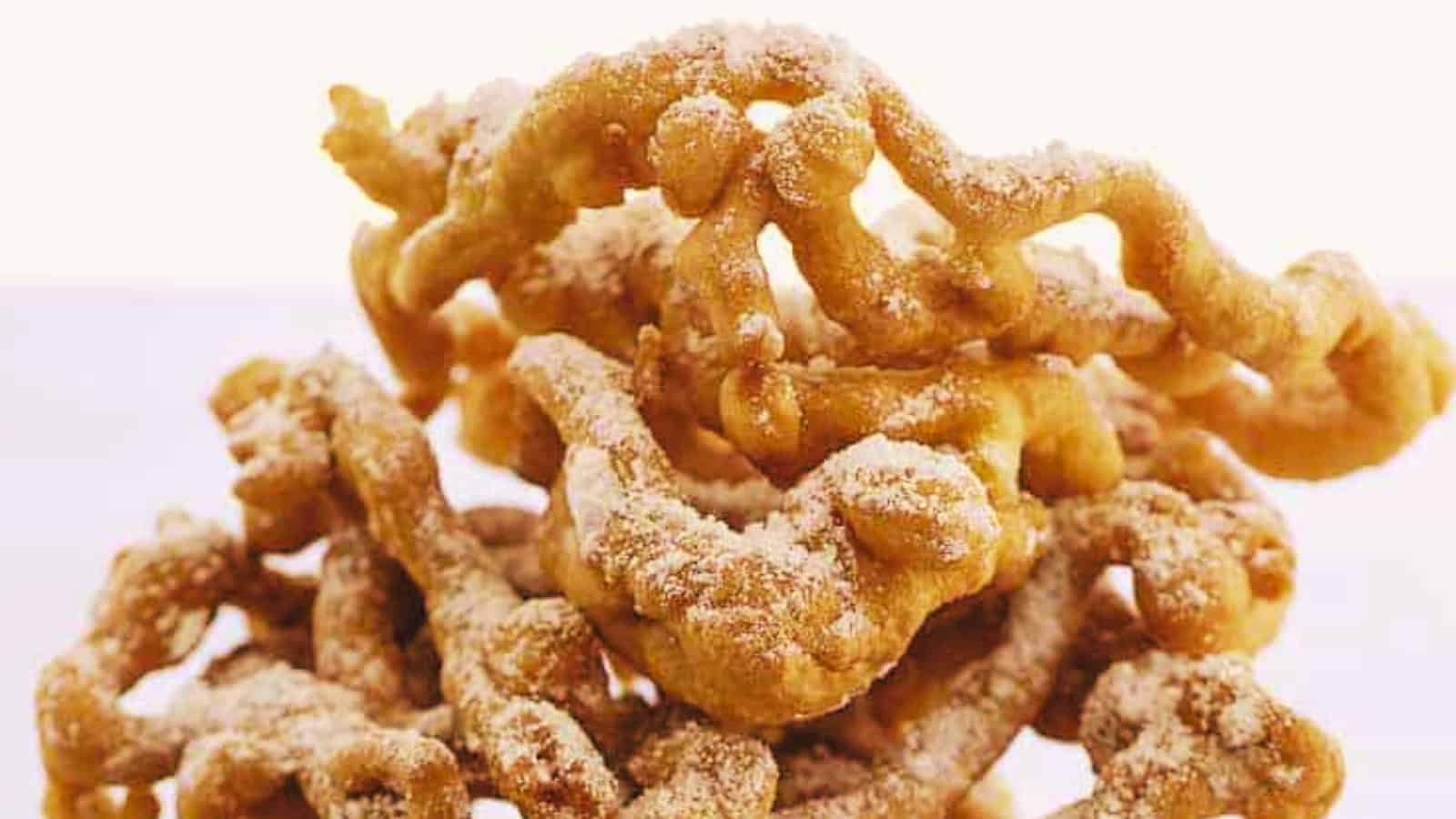 Golden, sugar-dusted funnel cakes stacked against a light background.
