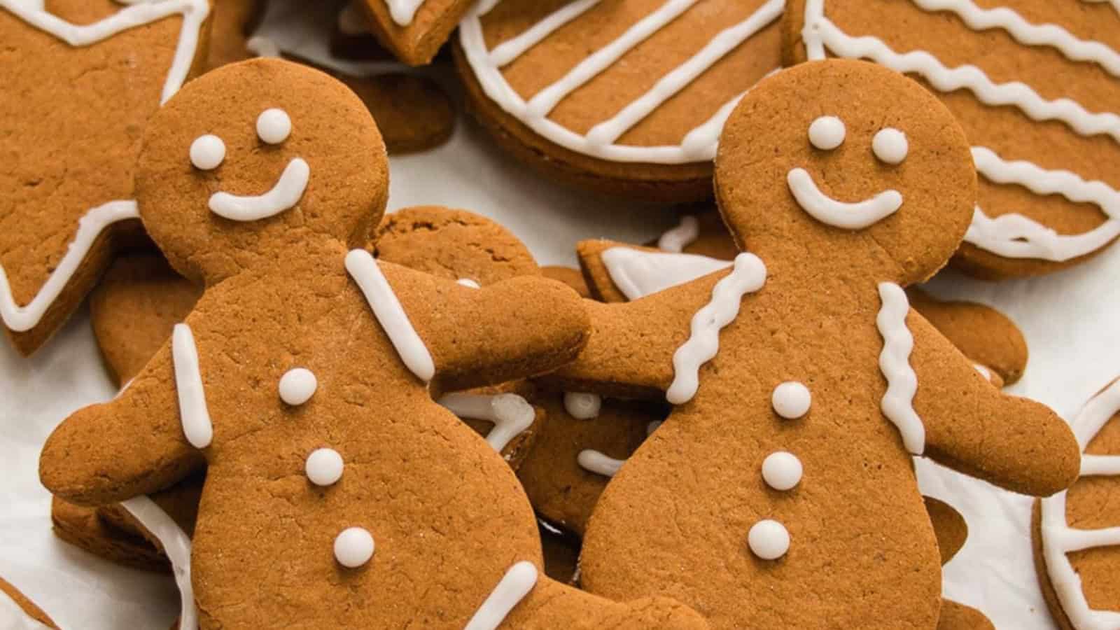 Two gingerbread cookies with white icing smiley faces and buttons, surrounded by decorated cookies.