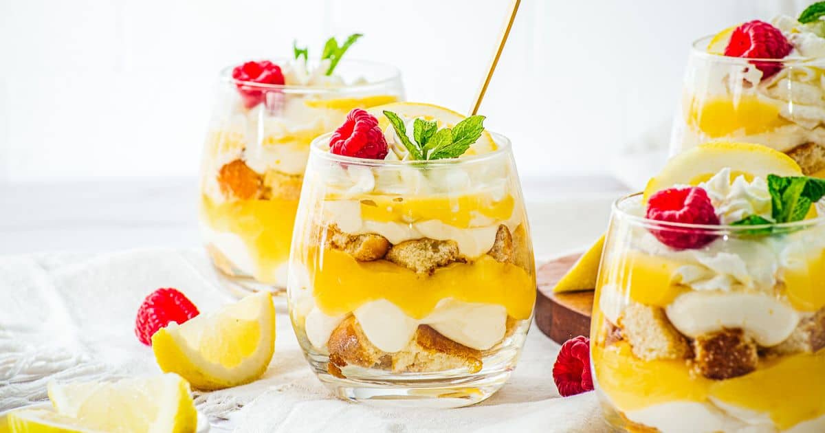 Lemon Cheesecake Trifle Cups are delightful individual dessert cups with layers of tangy lemon cream, soft cake, whipped topping, fresh raspberries, and a mint garnish.