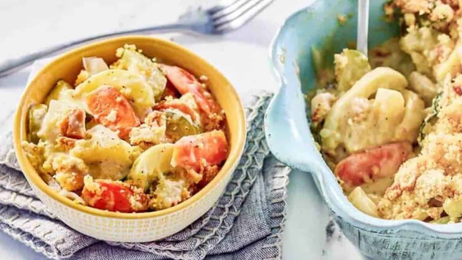 Bowl and dish of creamy baked vegetables with sliced potatoes and carrots on a textured napkin.