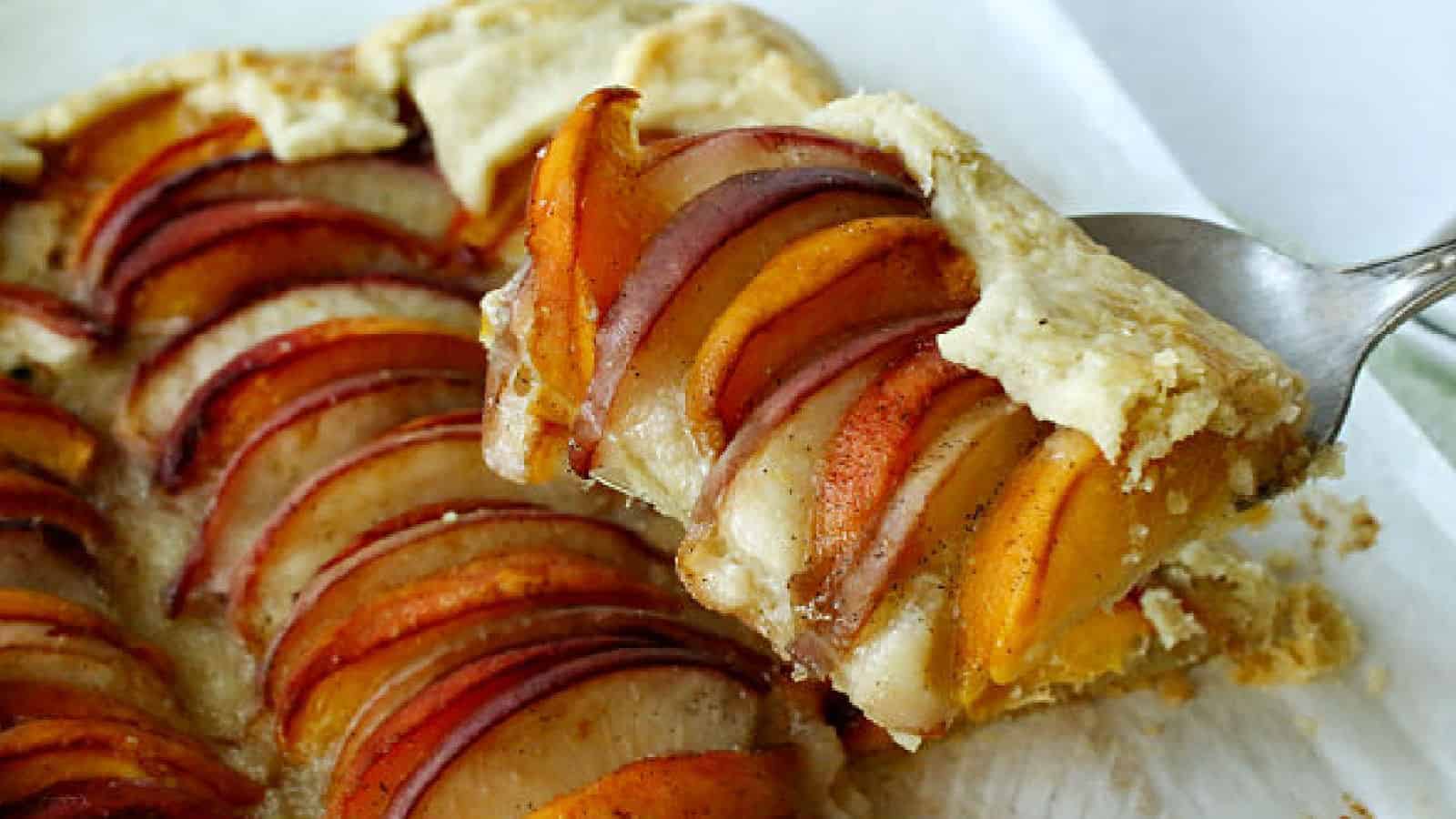 A slice of peach ttart on a white board.