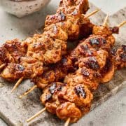 Grilled chicken skewers with visible char marks on a stone serving platter.