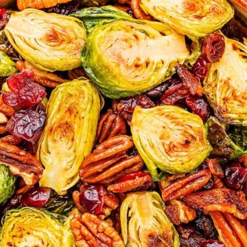 Roasted Brussels sprouts with pecans and dried cranberries in a bowl, viewed from above.
