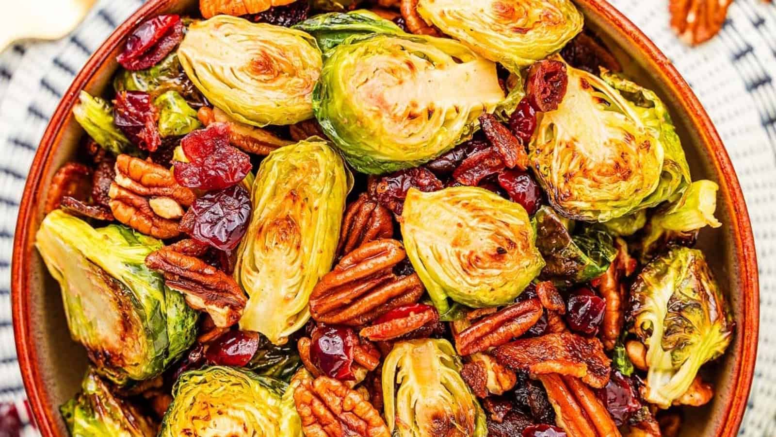 Roasted Brussels sprouts with pecans and dried cranberries in a bowl, viewed from above.