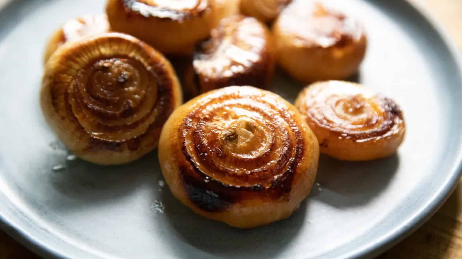 Smoked cipollini onions with browned, caramelized edges arranged on a plate.