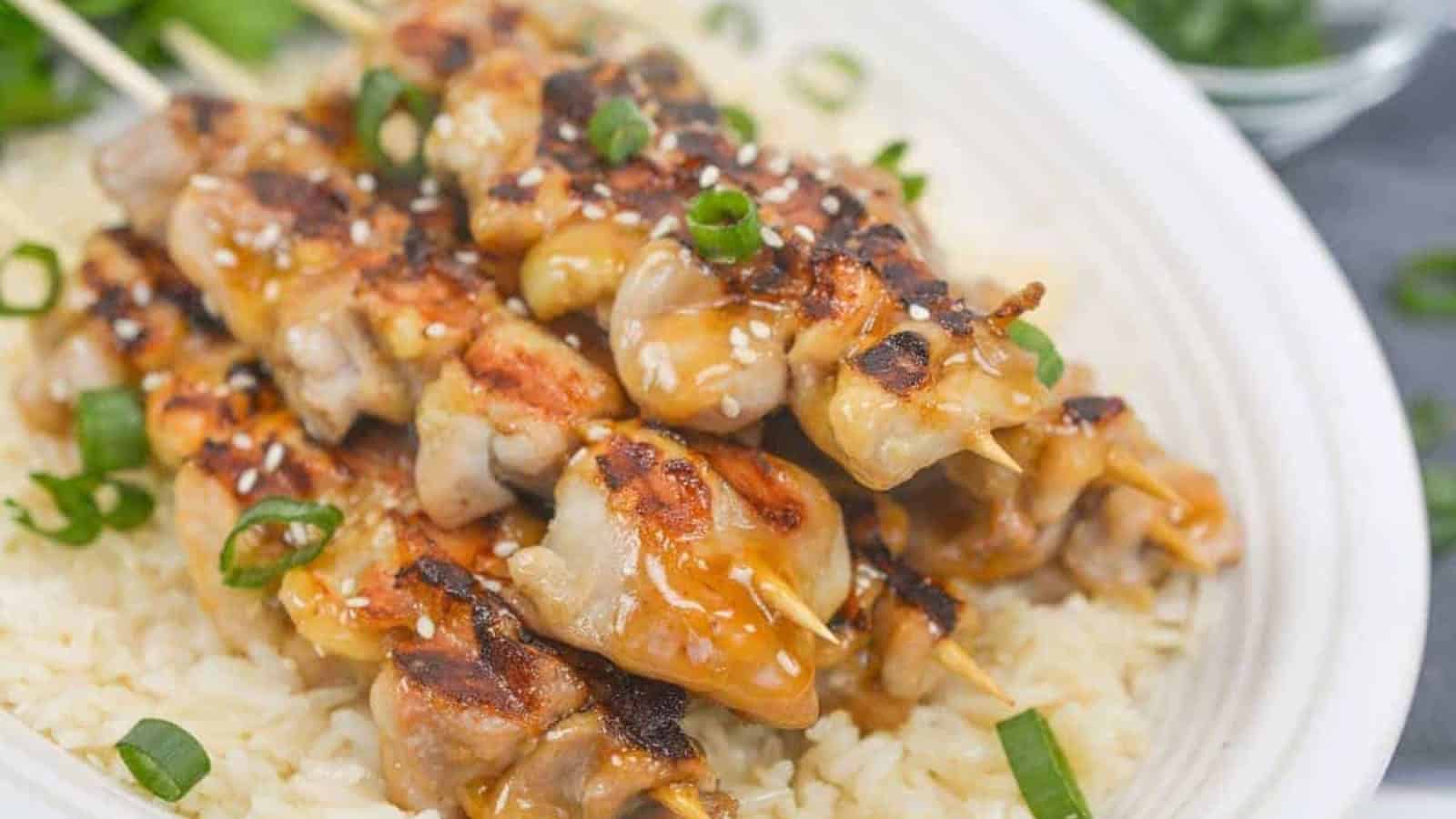 Asian chicken skewers on top of rice.