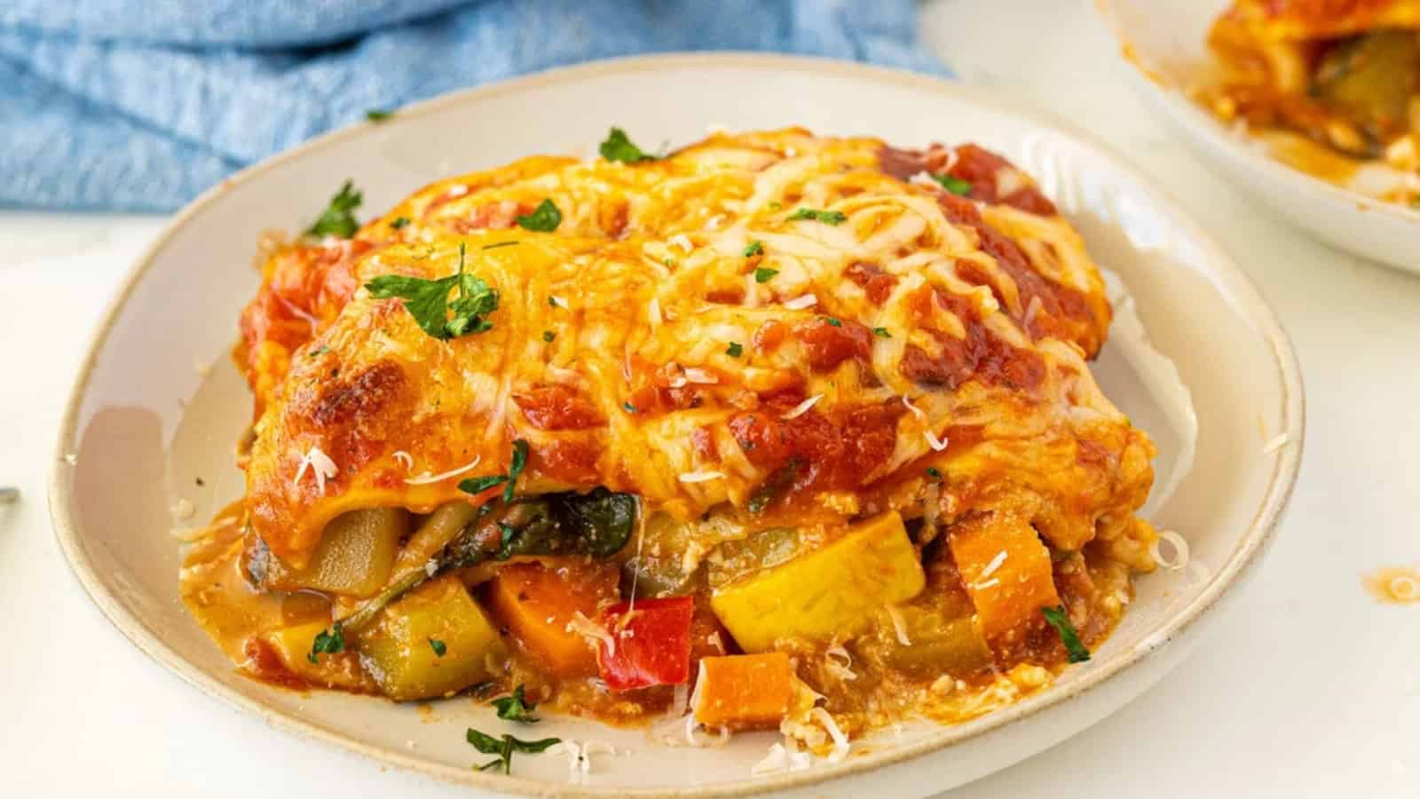 Slice of vegetable lasagna layered with pasta, vegetables, tomato sauce, and melted cheese.
